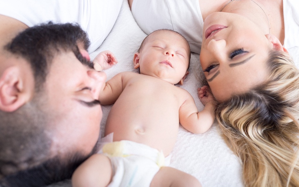New baby and parents lying on a bed